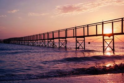 Bridge over sea against sky during sunset