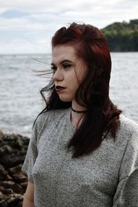 Portrait of young woman looking away while standing in sea