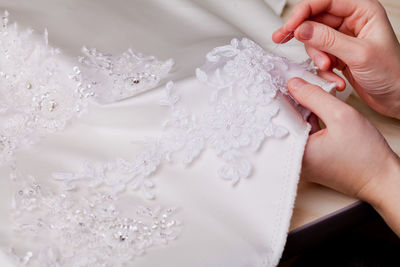 Cropped hands of woman stitching wedding dress