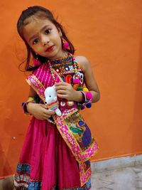 Portrait of cute girl standing against wall