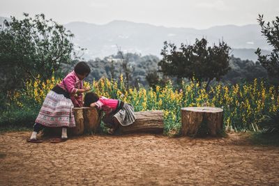 Rear view of women sitting on plants against mountains