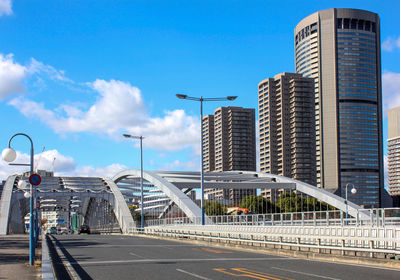 City street by modern buildings against sky