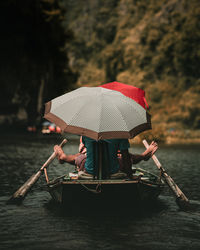 Man with umbrella on boat in river