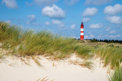 Lighthouse on beach against sky