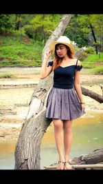 Portrait of a young woman standing against tree