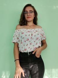 Portrait of beautiful young woman standing against wall