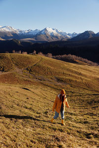 Rear view of woman standing on field against mountain