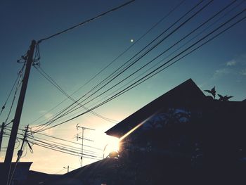 Low angle view of silhouette electricity pylon against sky during sunset
