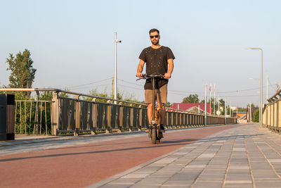 Attractive european man is riding on electric scooter with his small dog. walking with dog. 