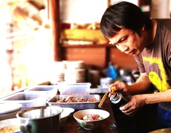 Mature man preparing food with butane torch in kitchen