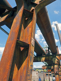 Low angle view of rusty metal bridge against sky