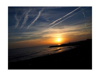 Scenic view of beach against sky at sunset