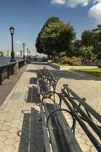 Footpath by street in city against sky