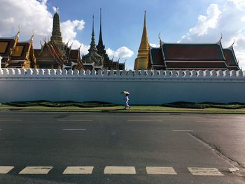 Mid distance view of woman under umbrella walking by grand palace