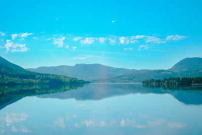 Scenic view of lake and mountains against blue sky