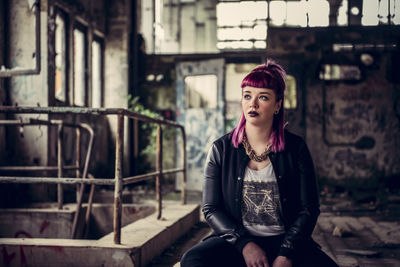 Woman looking away sitting in abandoned building