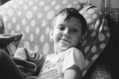 Portrait of boy smiling while lying on bed at home