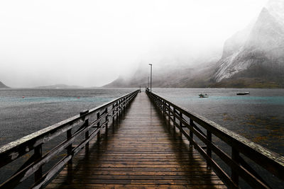 Wooden bridge pier at the coast against sky  in moskenesoya during winter in lofoten norway