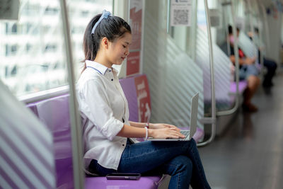 Side view of woman using mobile phone while sitting in bus