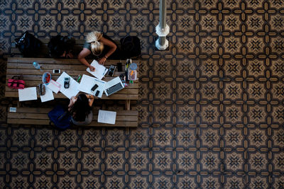 Directly above shot of people studying at desk on tiled floor