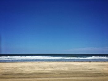 Scenic view of beach against clear blue sky