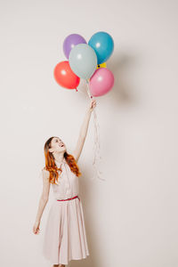 Low angle view of woman with balloons against white background