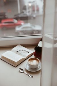 Book and coffee cup on window sill at home