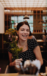 Smiling young woman holding ice cream in restaurant