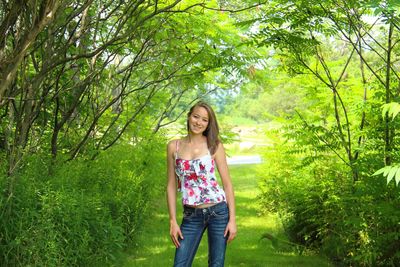 Portrait of young woman standing against plants