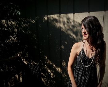 Young woman looking away while standing in backyard