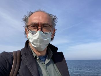 Portrait of man wearing mask against sea against sky