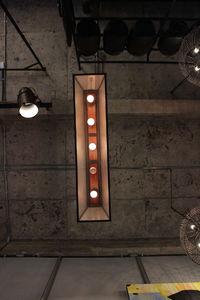 Low angle view of illuminated pendant light hanging on ceiling in building