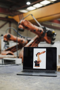 Laptop with robotic arm picture at desk in industry