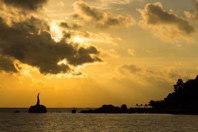 Silhouette statue by sea against sky during sunset