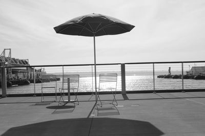 Deck chairs by swimming pool against sky