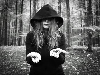 Woman wearing hat standing against trees in forest