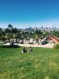 People sitting in park against clear sky