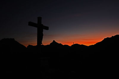 Silhouette cross against sky during sunset