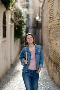 Smiling young woman walking in alley