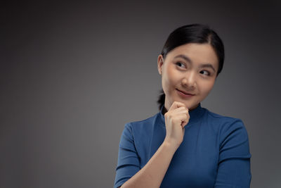 Portrait of a smiling young woman against gray background