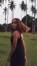 Portrait of young woman standing against trees