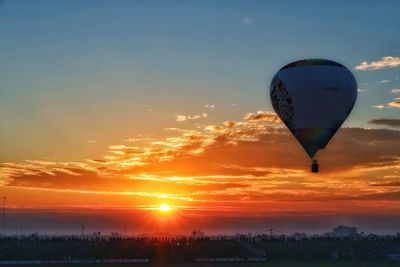 Hot air balloon flying over landscape against sky during sunset