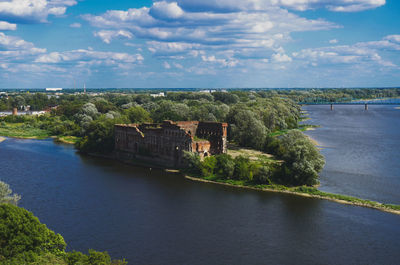 Scenic view of river by buildings against sky