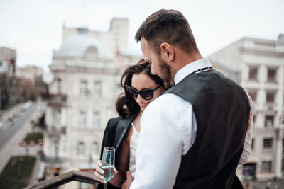 Bride holding champagne flute standing by railing outdoors