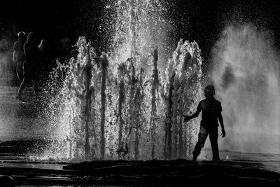 Silhouette man standing in water at night