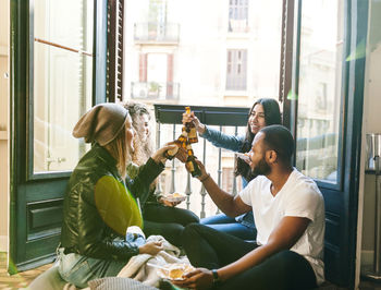 Four friends clinking beer bottles