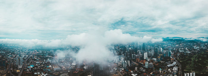 Panoramic view of city buildings against cloudy sky