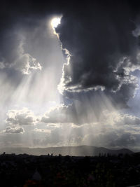 Low angle view of sunlight streaming through clouds