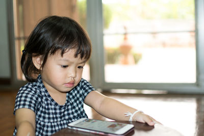 Cute girl looking at camera while sitting on table