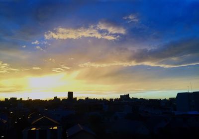 Silhouette houses against sky during sunset